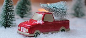 赤いトラックのおもちゃが雪の中でクリスマスツリーを運んでいる