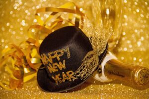 金色のシャンパンボトルが横たわっており、その前にHAPPY NEW YEARと書かれた黒い帽子がある