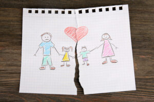 紙に夫婦と子ども二人の家族のイラストが描かれており、真ん中で破れている 